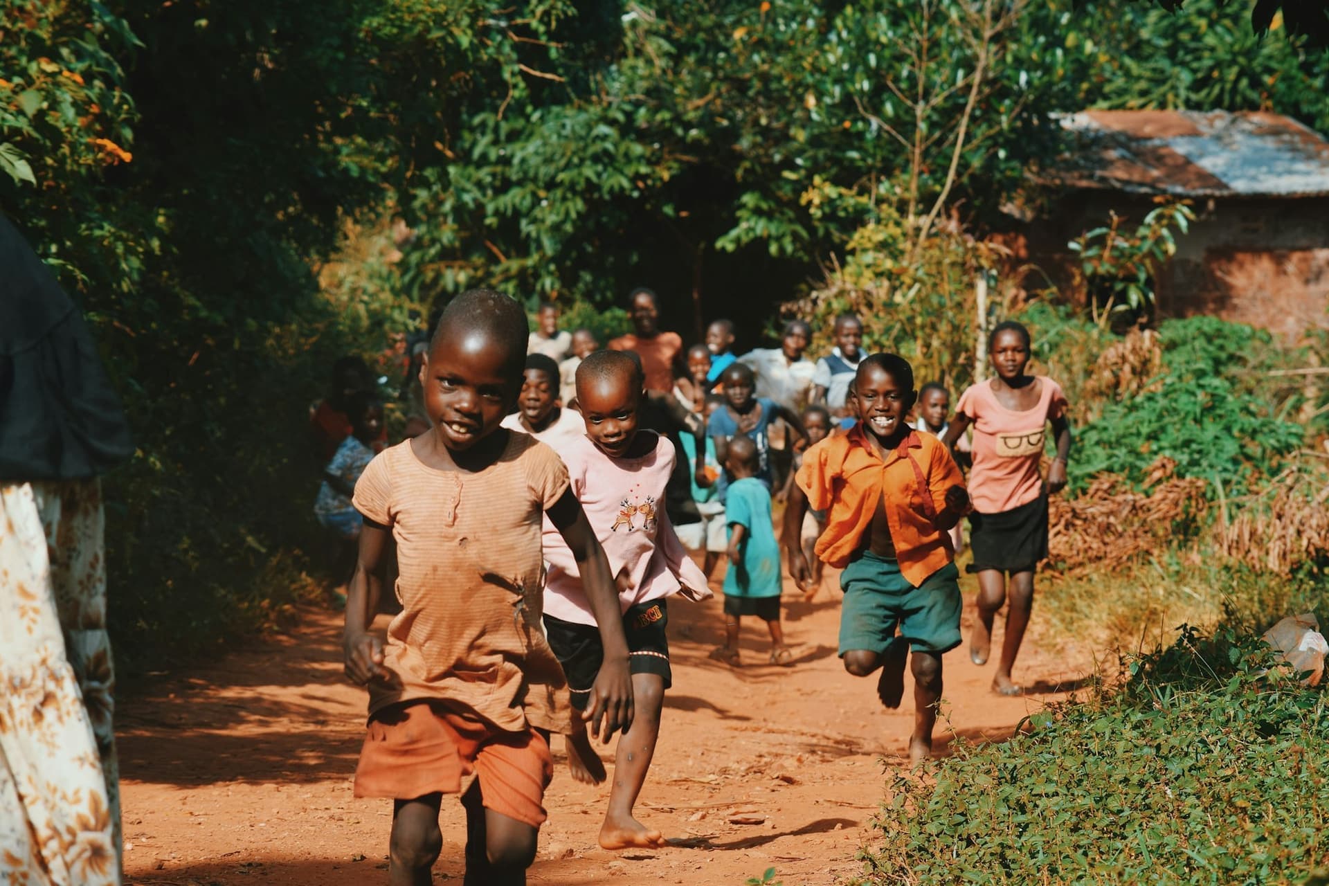Des enfants courent sur un chemin de terre entouré de verdure