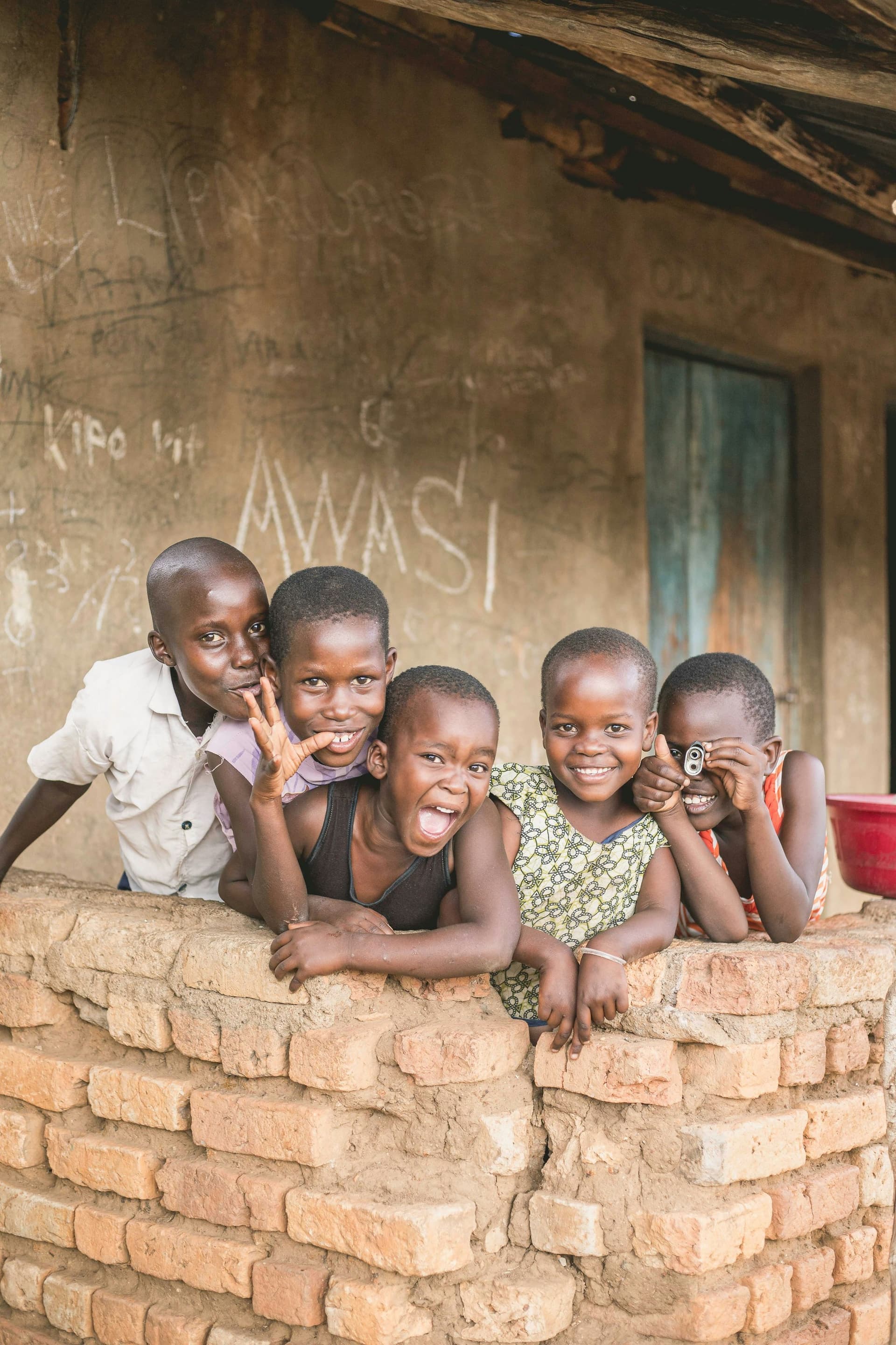 Un groupe d'enfants souriants devant un mur