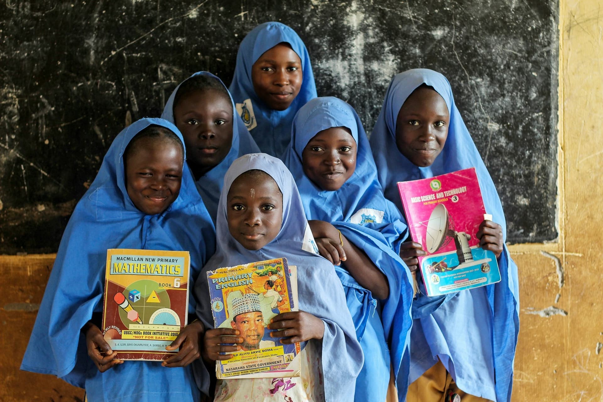 Des écolières en uniforme tiennent fièrement leurs manuels scolaires